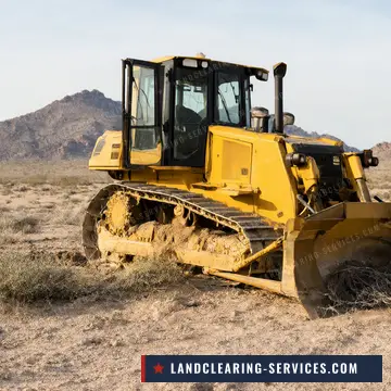 Crawler dozer clearing creosote and desert brush below rocky mountains