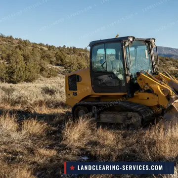 Crawler dozer clearing sagebrush on high country land with mountains behind